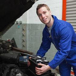 Portrait of happy male mechanic with battery by car Portrait of happy male mechanic with battery by car