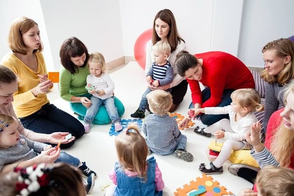 Children with mothers sit in a circle and study colors, numbers and figures in the kindergarten