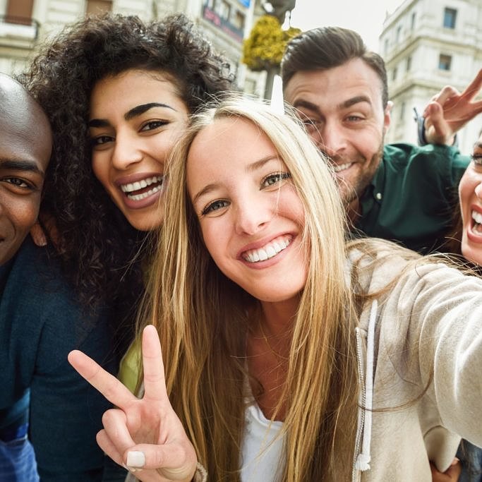 Multiracial group of young people taking selfie Multiracial group of friends taking selfie in a urban street with a blonde woman in foreground. Three young women and two men wearing casual clothes.